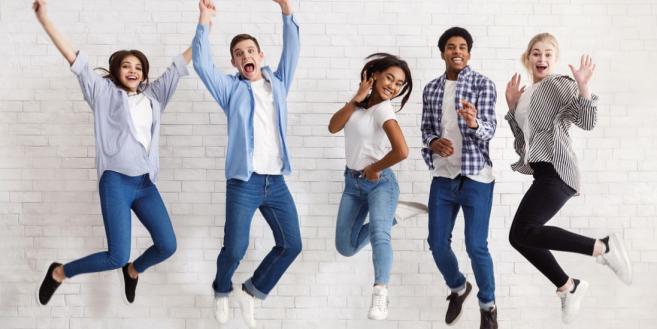 fünf Jugendliche springen in die Luft und lachen in die Kamera