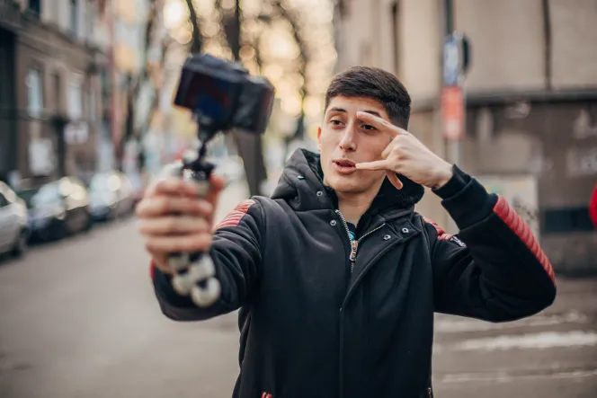 ein junger Mann hält einen Selfiestick in der Hand und filmt sich selbst.