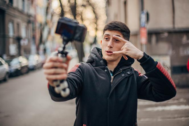 ein junger Mann hält einen Selfiestick in der Hand und filmt sich selbst.
