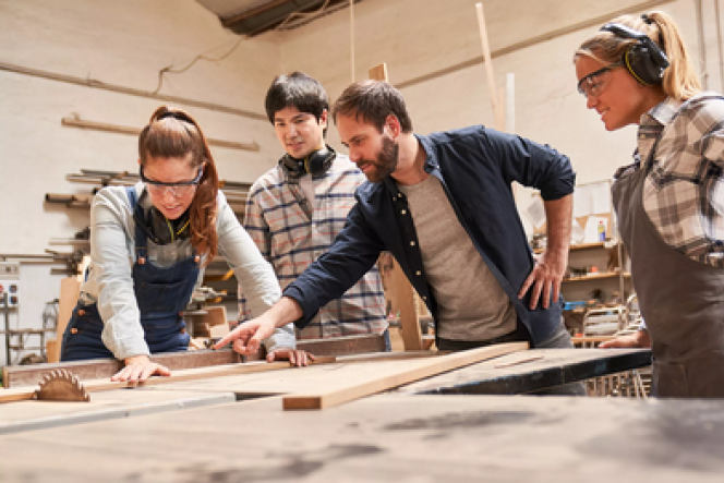 3 Jugendliche stehen mit ihrem Ausbilder in der Werkstatt