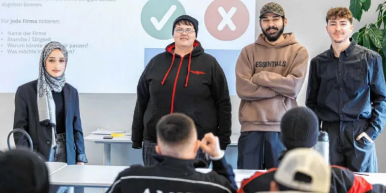Vier Jugendliche stehen vor einer Klasse