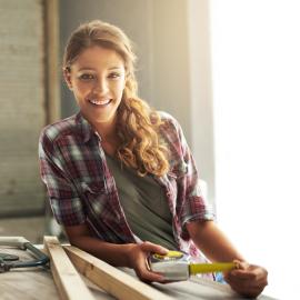 Ein Mädchen lehnt an einer Hobelbank und lächelt in die Kamera.